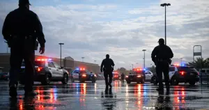 Police vehicles with flashing emergency lights in a large retail store parking lot during daytime response
