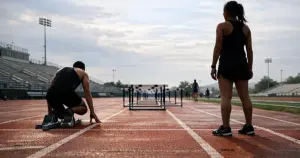 Empty high school track and field facility with lanes and hurdles under overcast sky