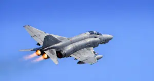Greek F-4 Phantom fighter jet banking during low-altitude maneuver against clear sky at air show