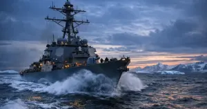 U.S. Navy warship navigating through Arctic waters at dusk with ice formations on horizon