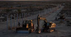 Idle construction equipment at desert border fence site in Big Bend region at dusk with mountains in distance