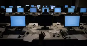Empty call center workstations with glowing monitors and abandoned headsets in dim lighting