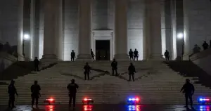 Law enforcement silhouettes positioned on state capitol building steps at dusk with emergency lights